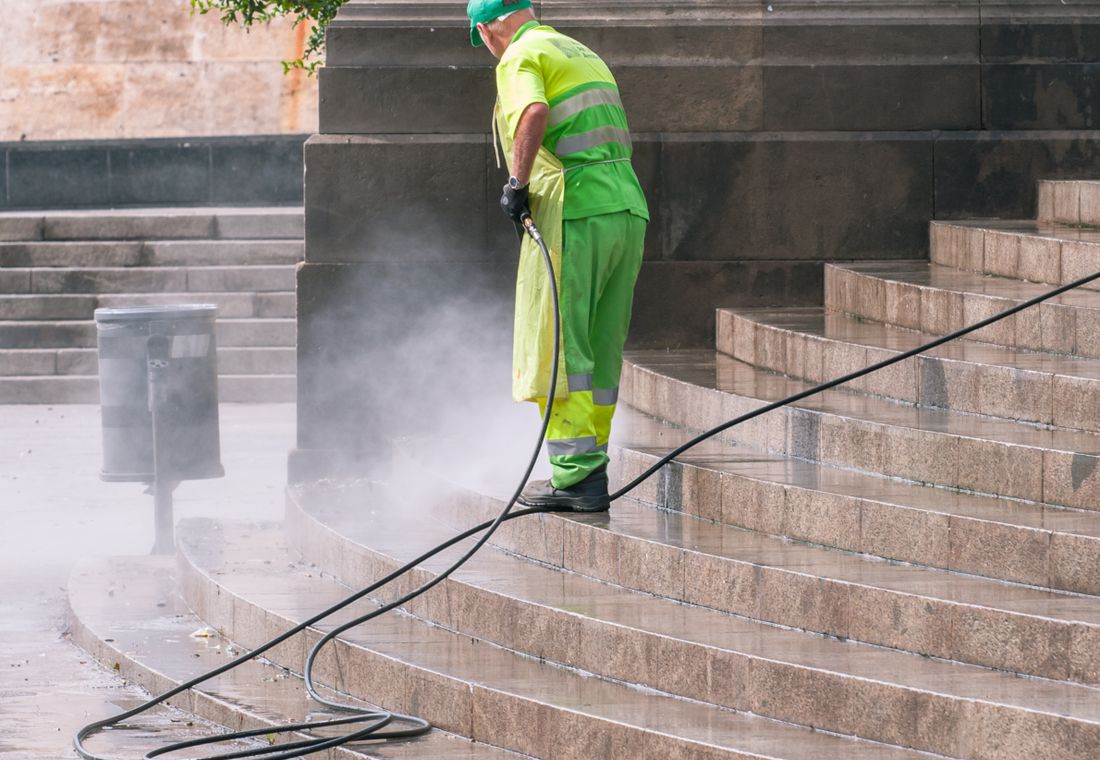 Operator pressure washing a paved surface